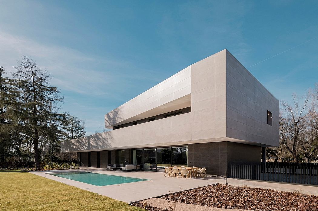 A modern, minimalist building with clean lines, glass walls, and a sleek pool.