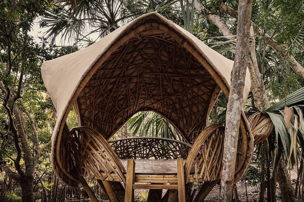 Ornate, domed structure of woven bamboo and thatch nestled in lush tropical foliage.