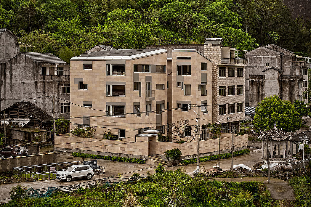 A modern, multi-story building with a mix of concrete and glass, surrounded by lush greenery.