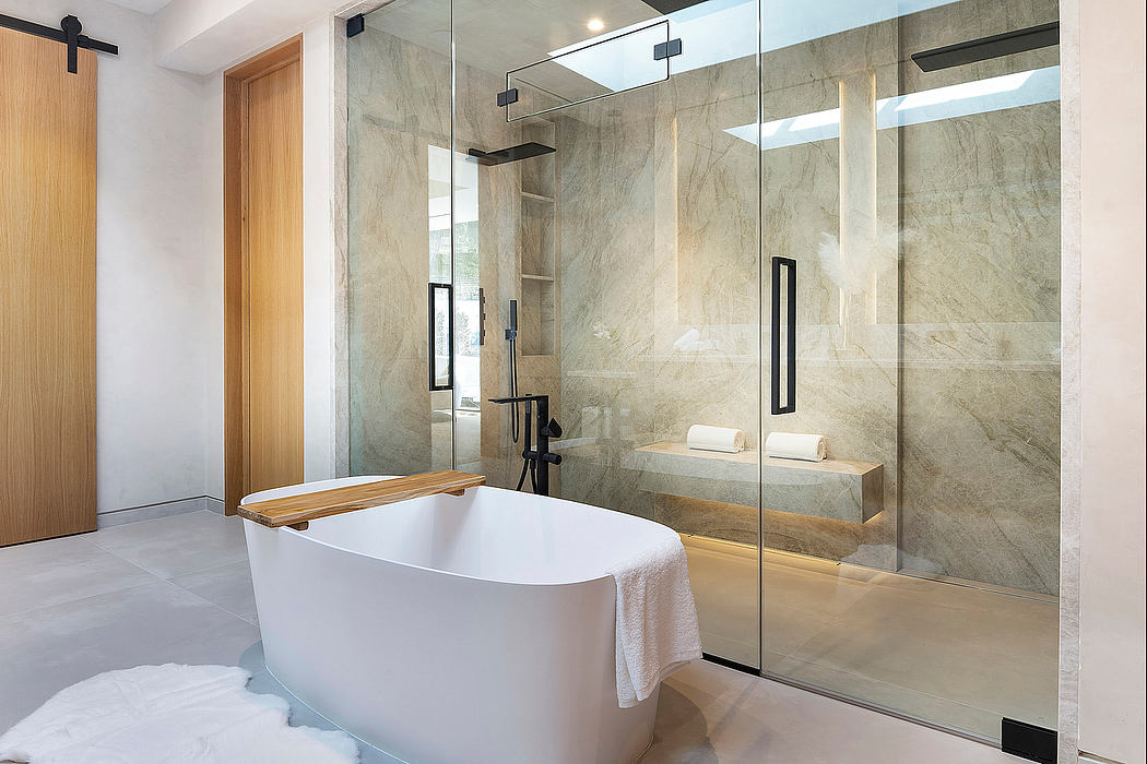 Spacious bathroom with sleek, modern design featuring marble walls and a freestanding tub.