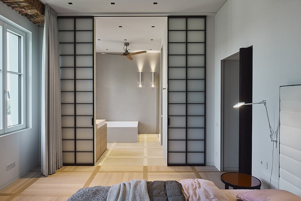Minimalist bedroom with sliding partition walls, wooden floor, and modern lighting.