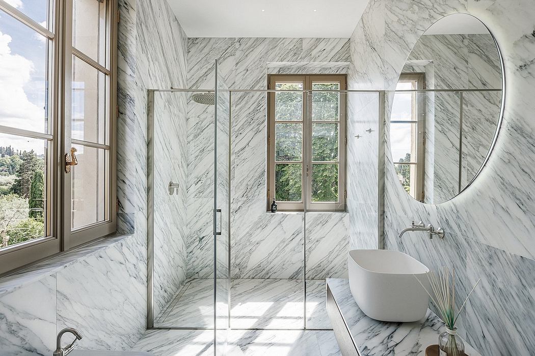 Lavish marble bathroom with modern fixtures, bathtub, and large window overlooking nature.