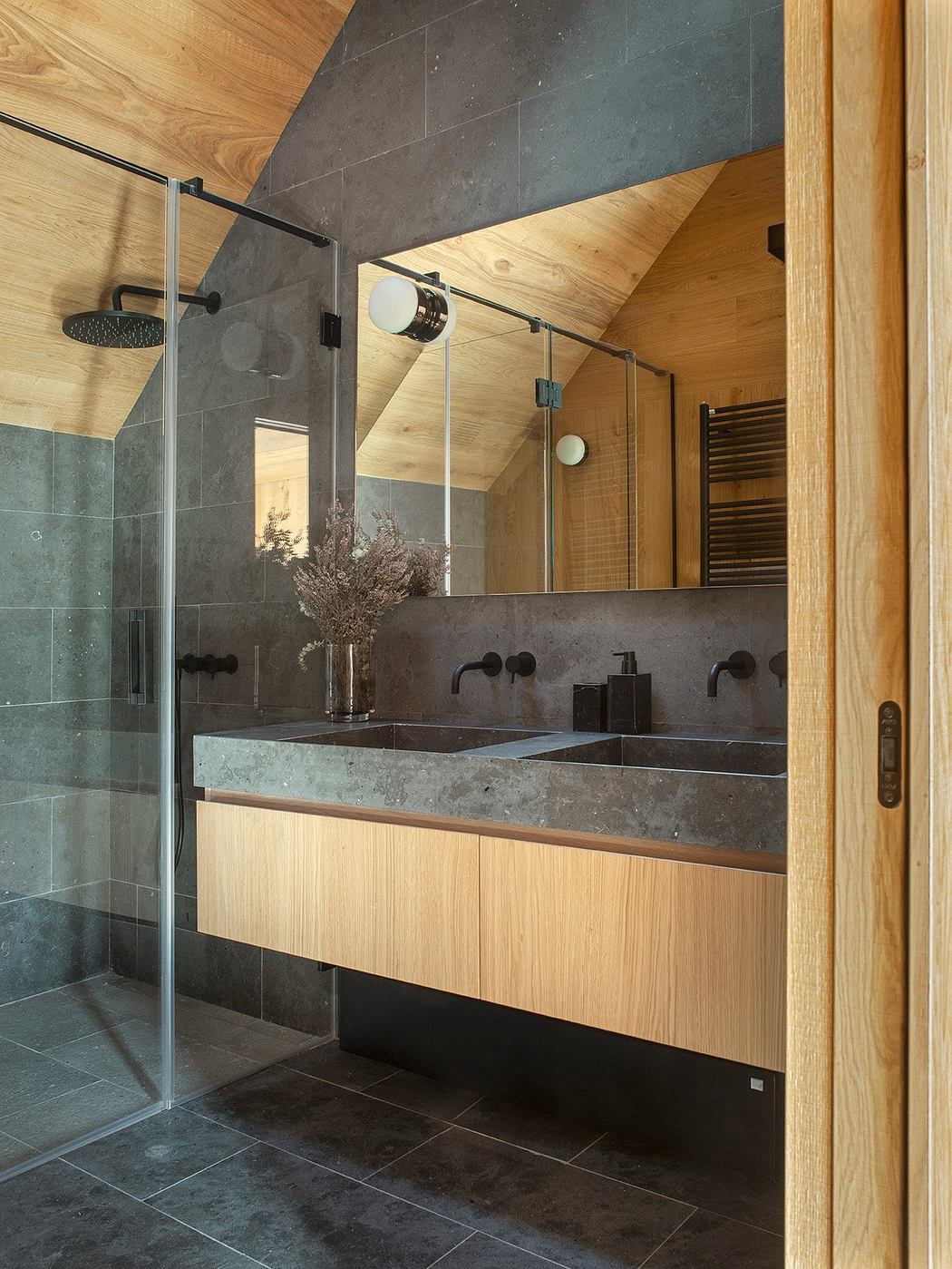 A modern bathroom with wooden paneling, double vanity, and glass shower enclosure.