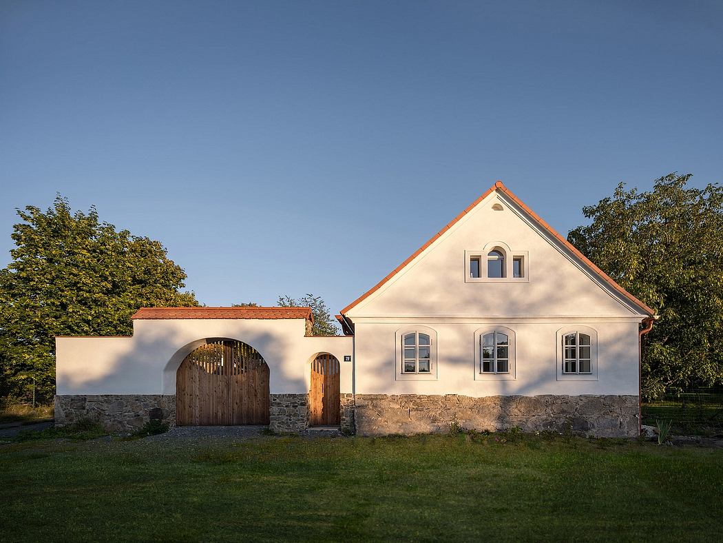 A traditional German farmhouse with a stone wall, wooden gates, and a red-tiled roof.