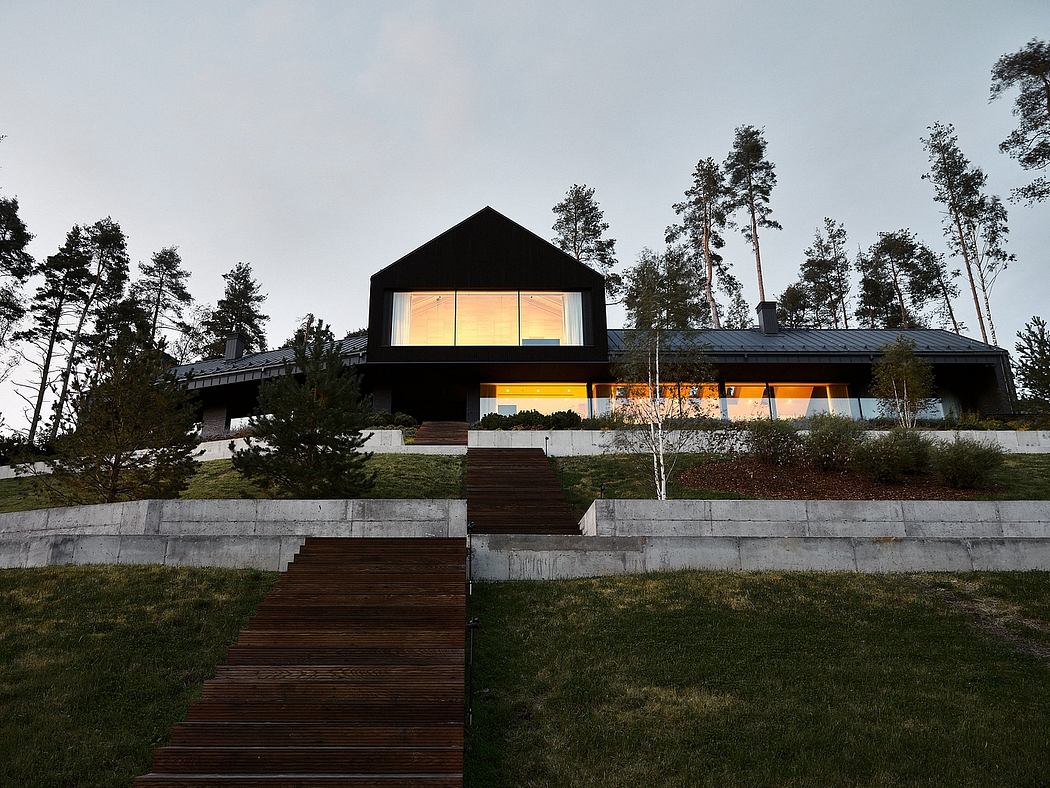 Modern two-story home with striking angular design, large windows, and wooden stairs leading up to the entrance.