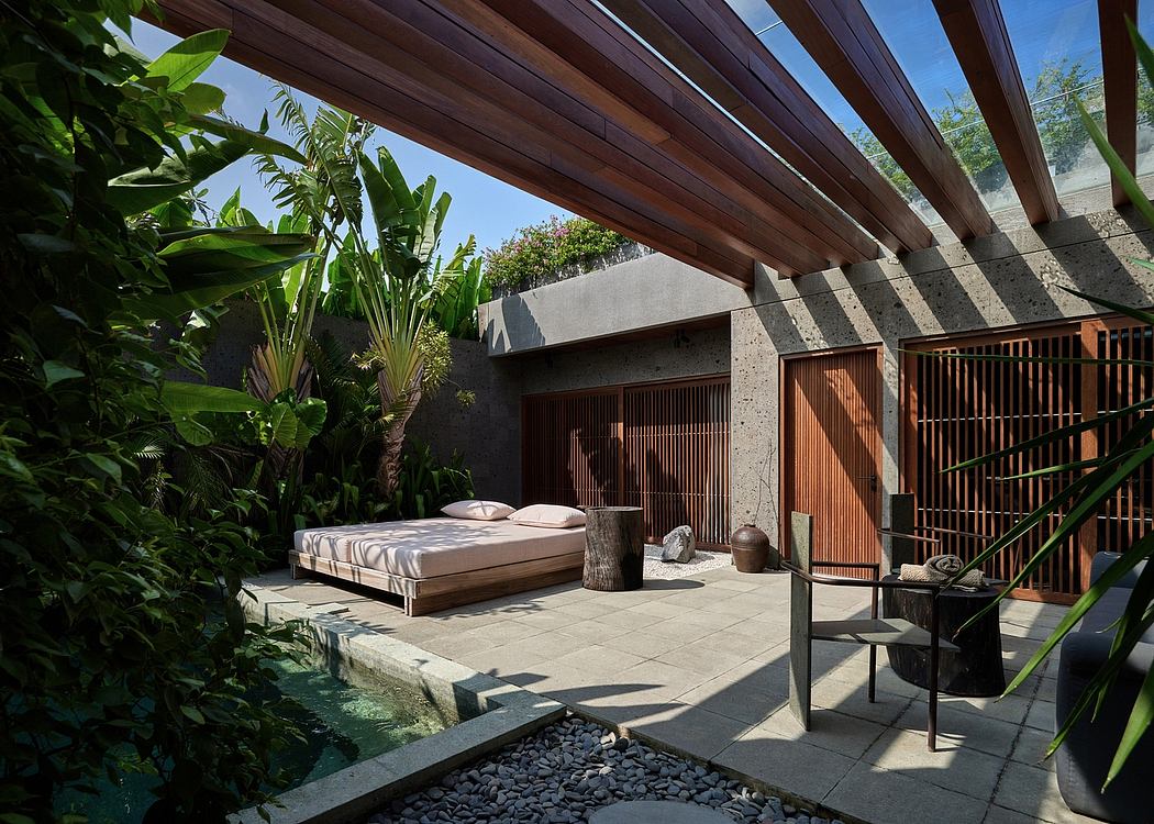 Lush tropical courtyard with wooden beams, stone tiles, and an outdoor daybed.