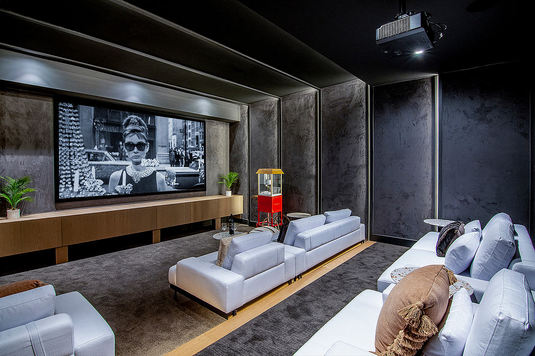 Sleek, minimalist home theater with large projection screen, modern furniture, and dark walls.
