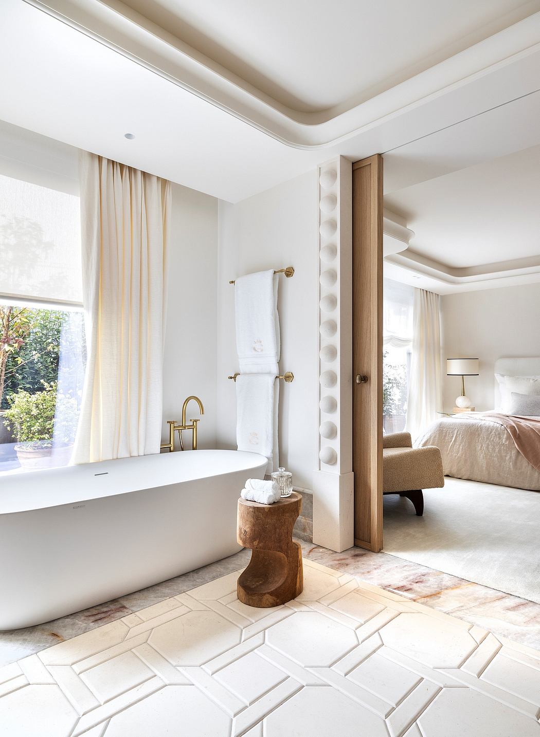 Modern, open-concept bathroom with freestanding tub, elegant fixtures, and patterned floor tiles.