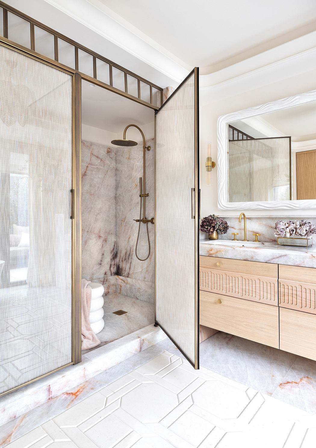 Luxurious bathroom with brass fixtures, marble surfaces, and modern geometric tiling.