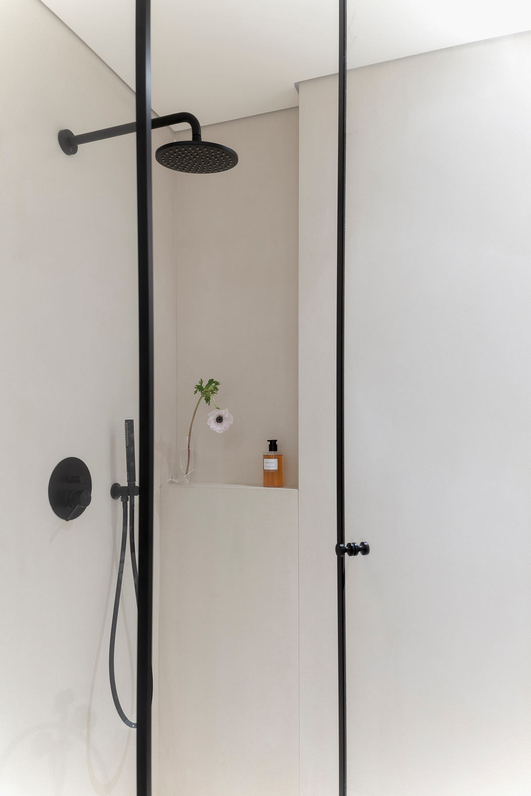 Minimalist bathroom design with black fixtures, built-in niche, and a flower decor.