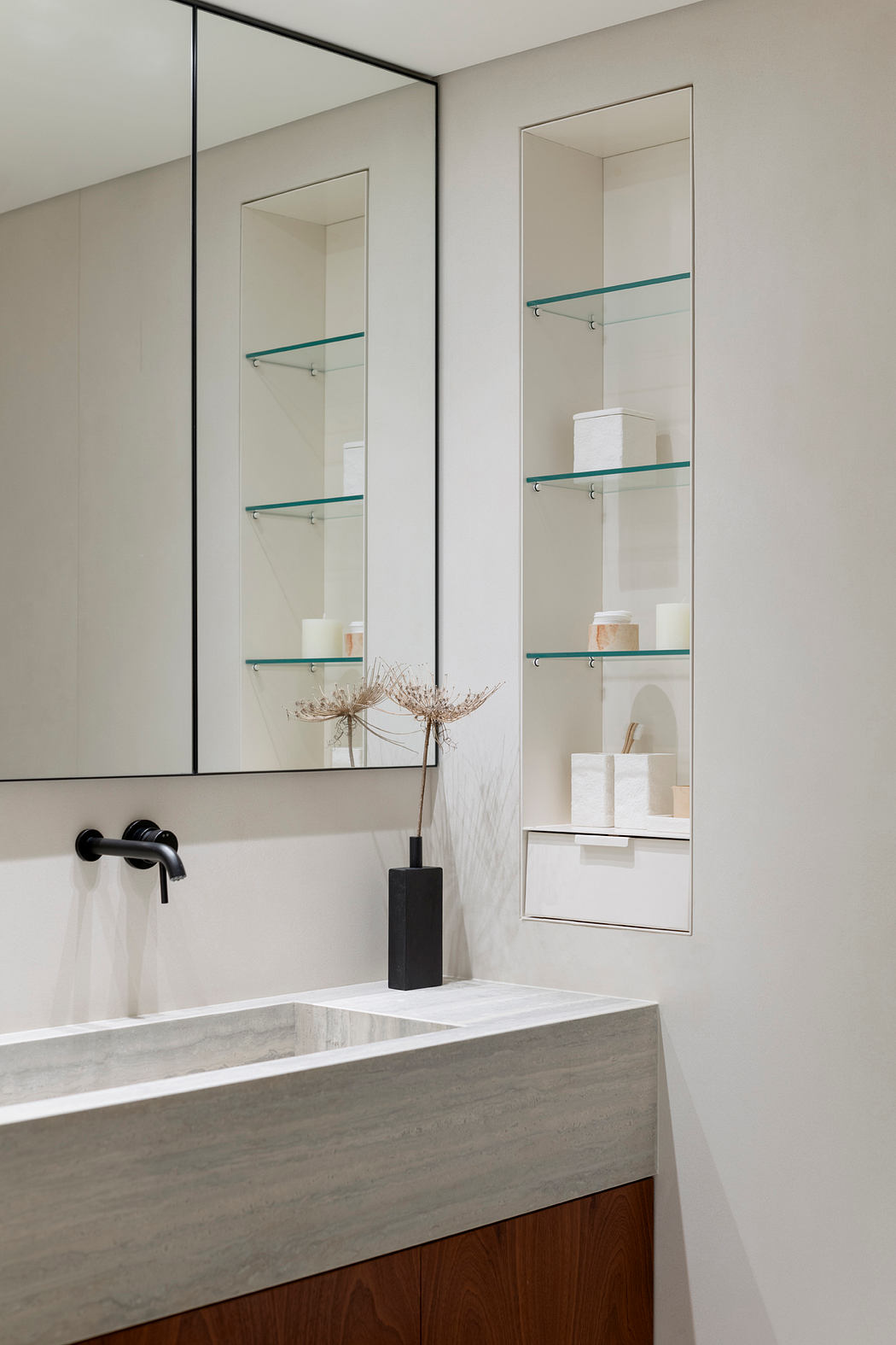 Modern minimalist bathroom with sleek vanity, glass shelves, and black fixtures.