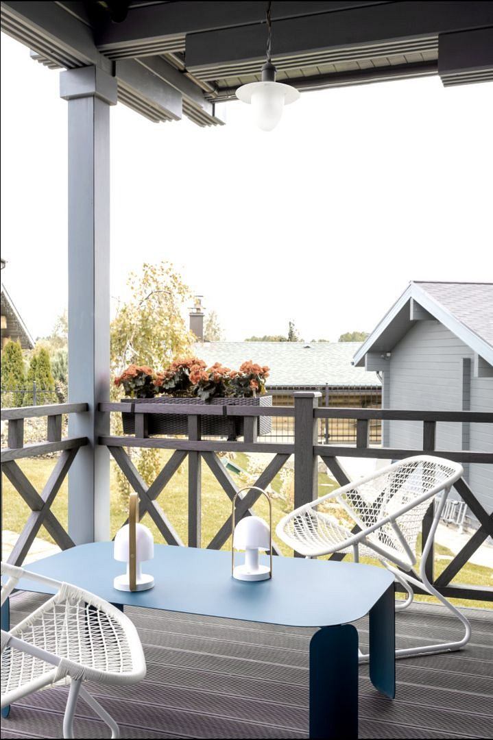 A cozy outdoor patio with modern furniture, lighting, and a view of surrounding buildings.