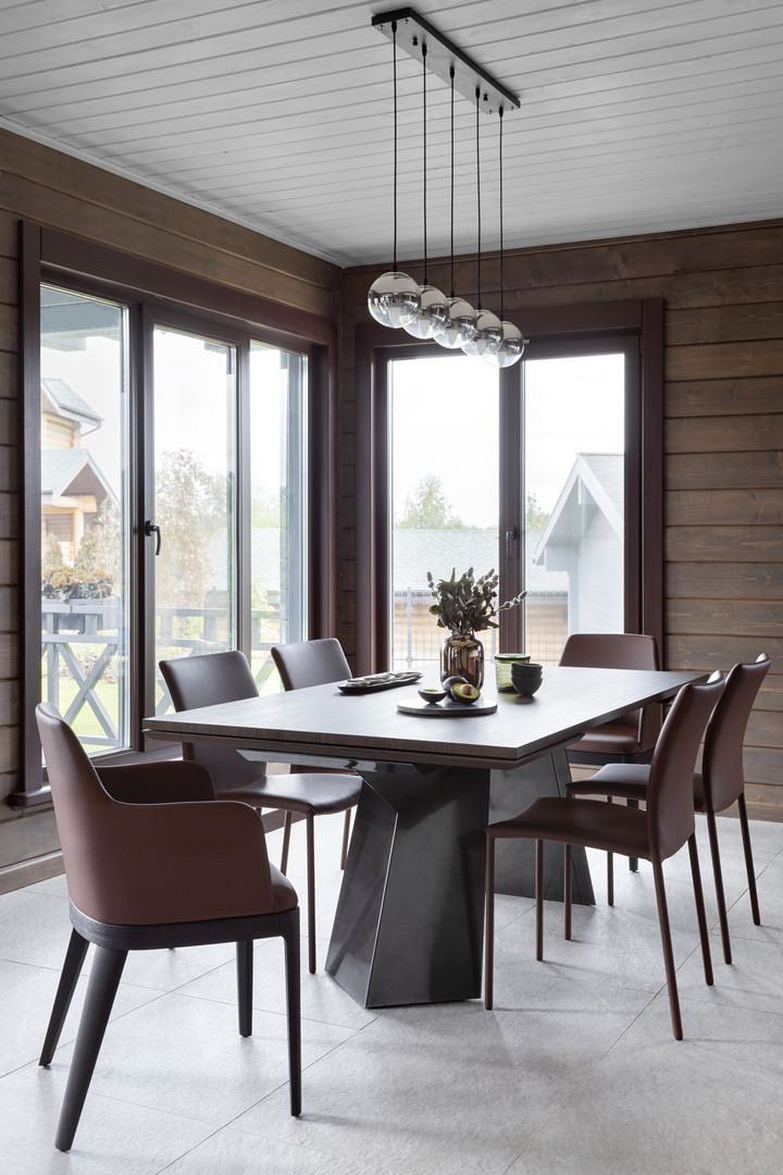 Modern dining room with a large table, leather chairs, and a sleek light fixture above.