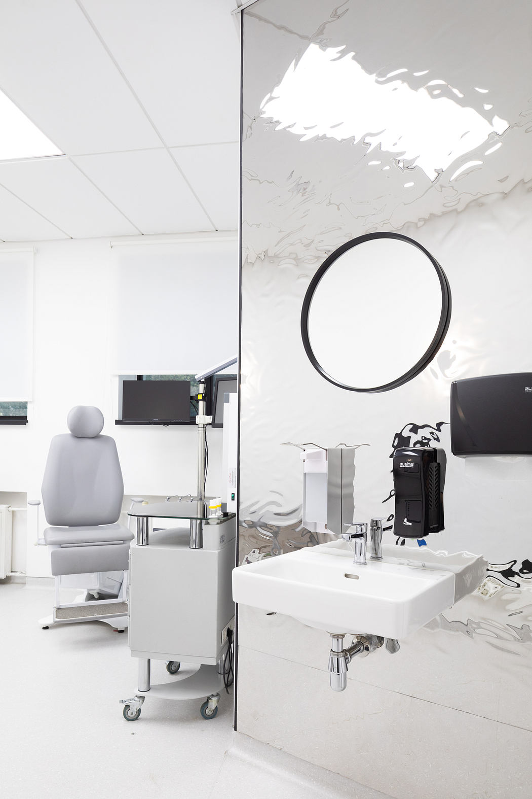 A minimalist medical office with a circular mirror, clinical equipment, and a monochromatic color scheme.