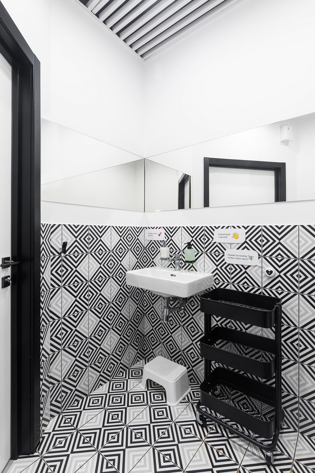 Striking monochrome bathroom with geometric tiled walls and minimalist black fixtures.