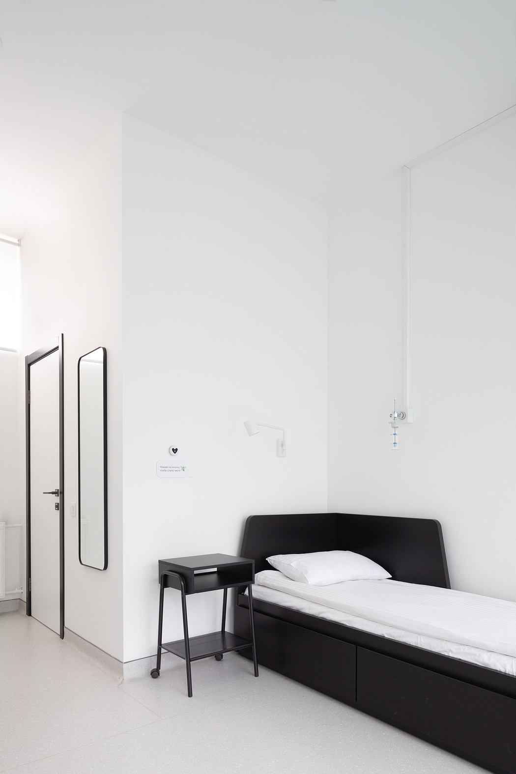 Minimalist bedroom with black bed frame, side table, and white walls. Simple, clean design.