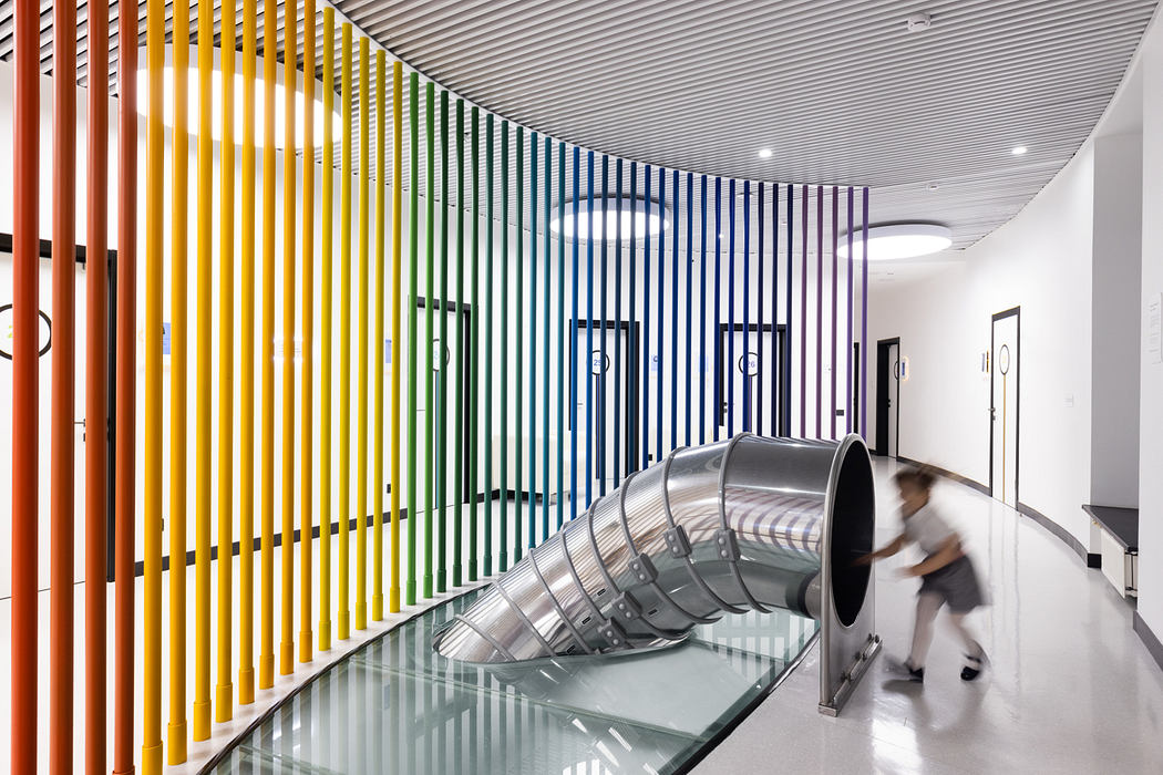 Vibrant, colorful architectural column design with curving metal slide in modern interior.