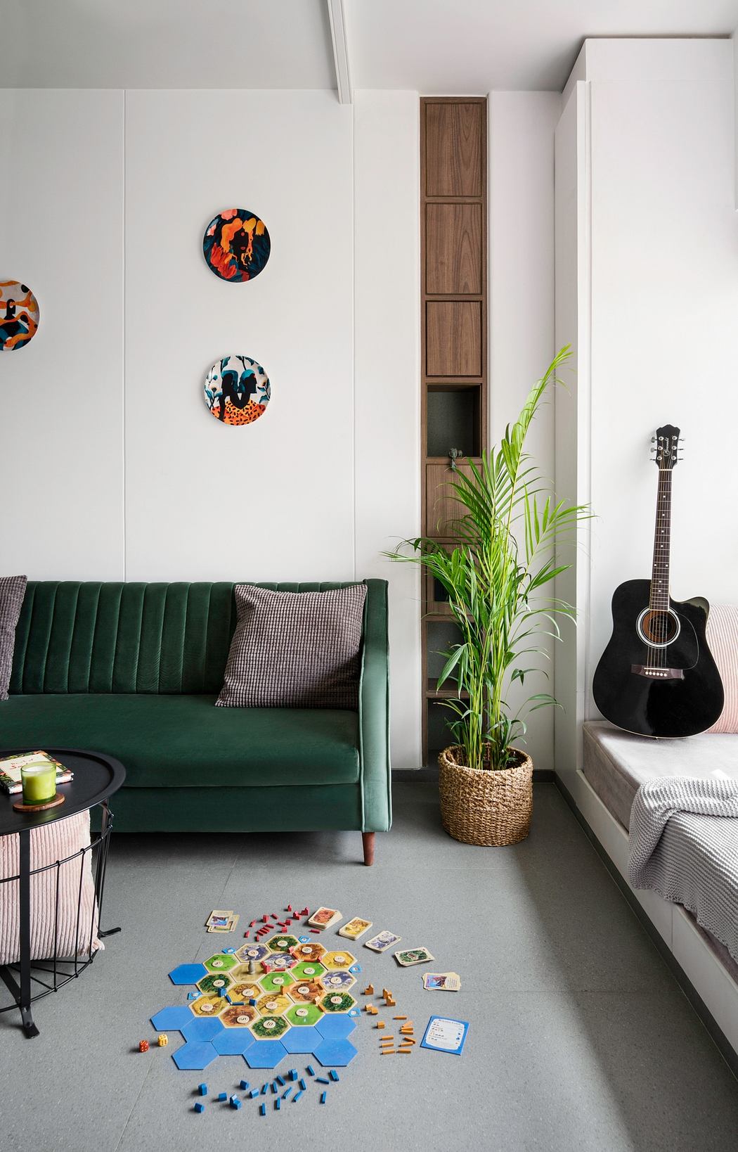 Cozy living room featuring a green velvet sofa, modular shelving, and a guitar.