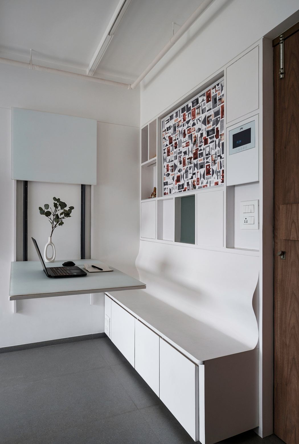 A modern home office featuring a sleek desk, built-in cabinetry, and a vibrant photo collage wall.