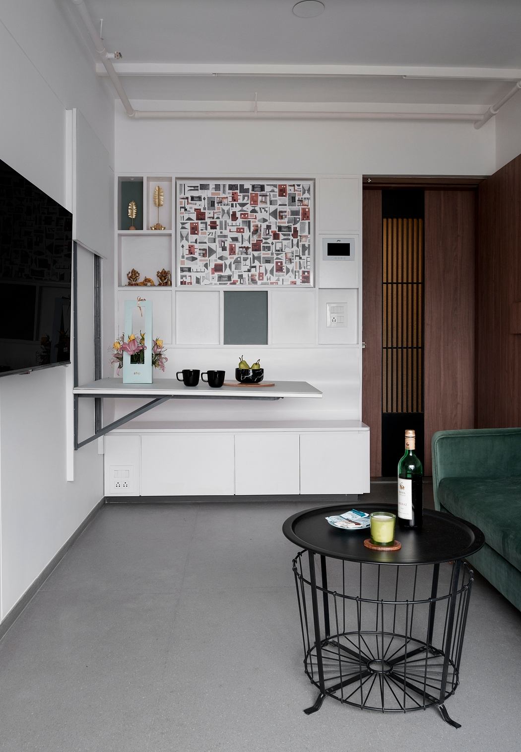 A contemporary living space featuring a white wall gallery, built-in shelves, and minimalist furnishings.