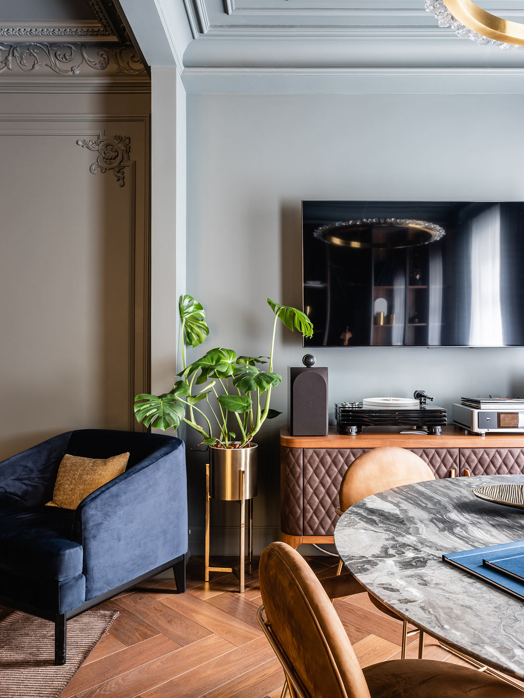 Opulent living room with ornate architectural details, marble table, and modern furniture.