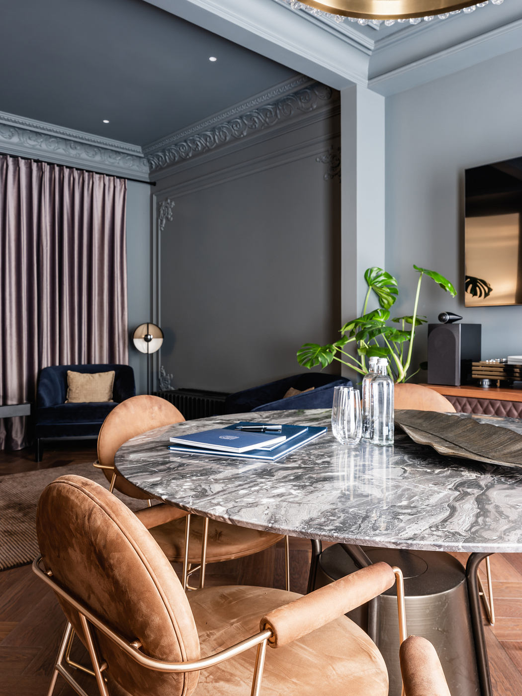 Elegant dining room with ornate molding, luxurious marble table, and plush leather chairs.