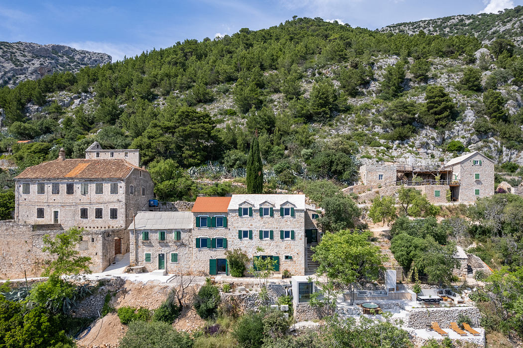 Picturesque village nestled in lush mountains, with rustic stone buildings, terraces, and foliage.