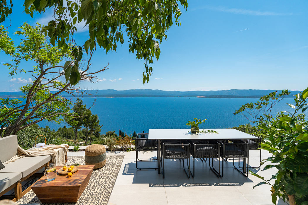 Elegant outdoor seating area with scenic ocean backdrop and lush foliage.