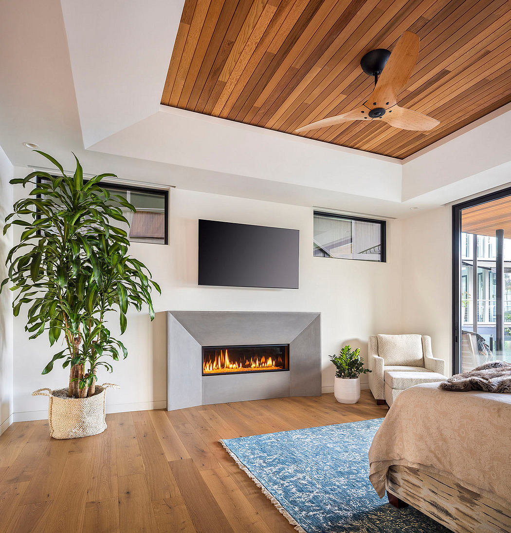 Cozy living room with wood-paneled ceiling, fireplace, and lush greenery.