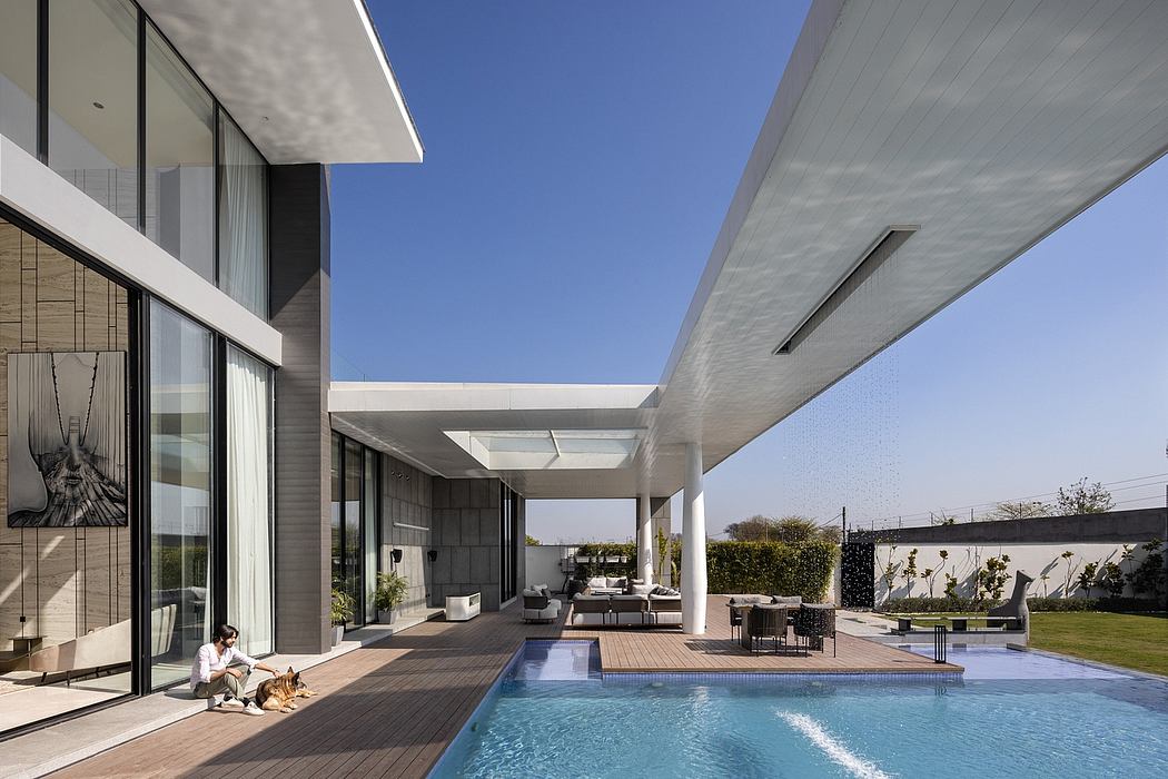 Modern, sleek architectural design with an outdoor pool area, seating, and lush greenery.