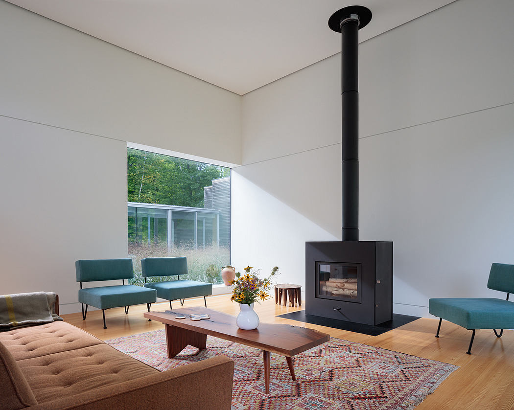 Spacious living room with wood-burning stove, plush seating, and floor-to-ceiling windows showcasing the lush outdoor scenery.