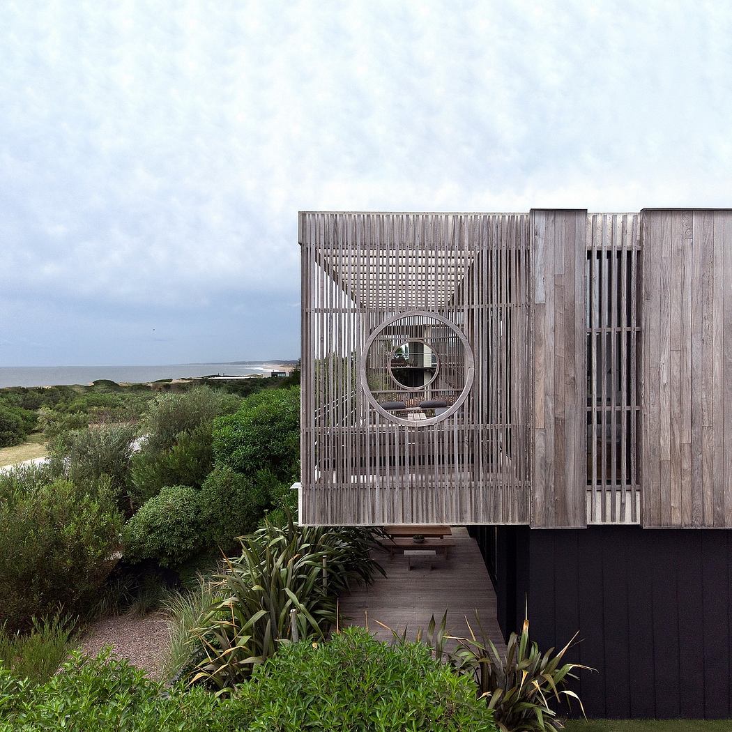 A wooden structure with a circular window and a lush, natural landscape in the foreground.