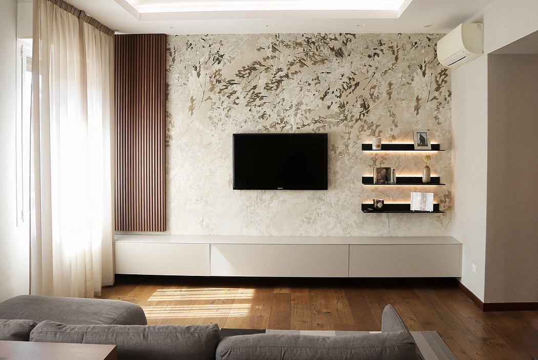 A modern living room with a large TV mounted on a patterned marble wall and floating shelves.