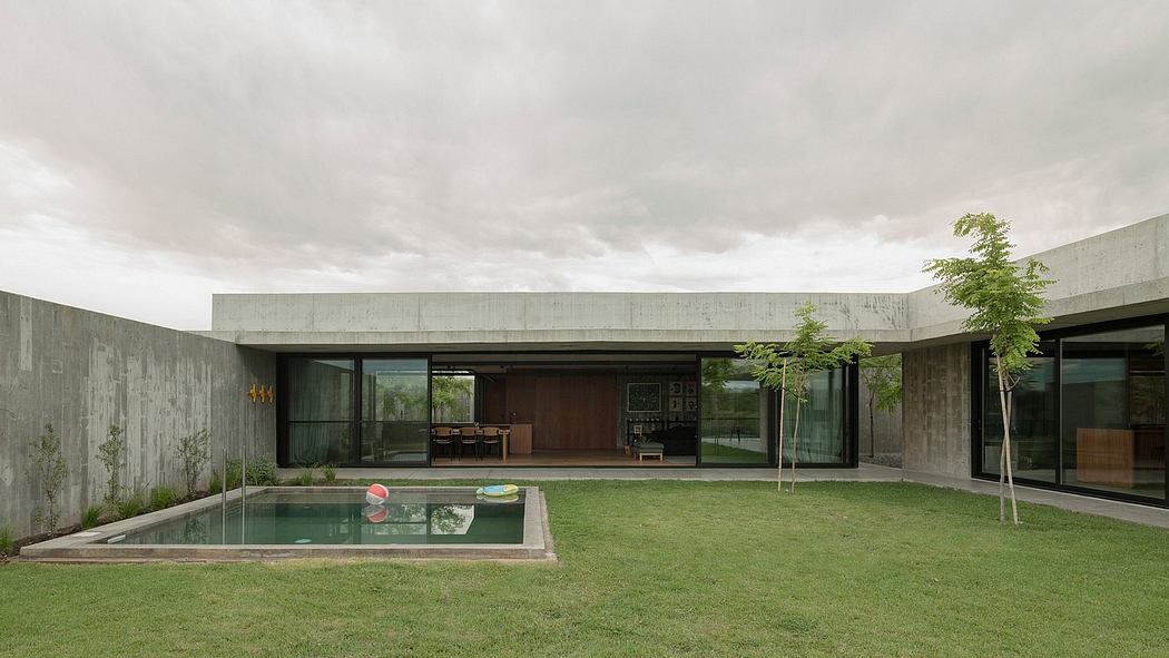 Modern concrete house with pool and lush greenery surrounding the open-plan interior.