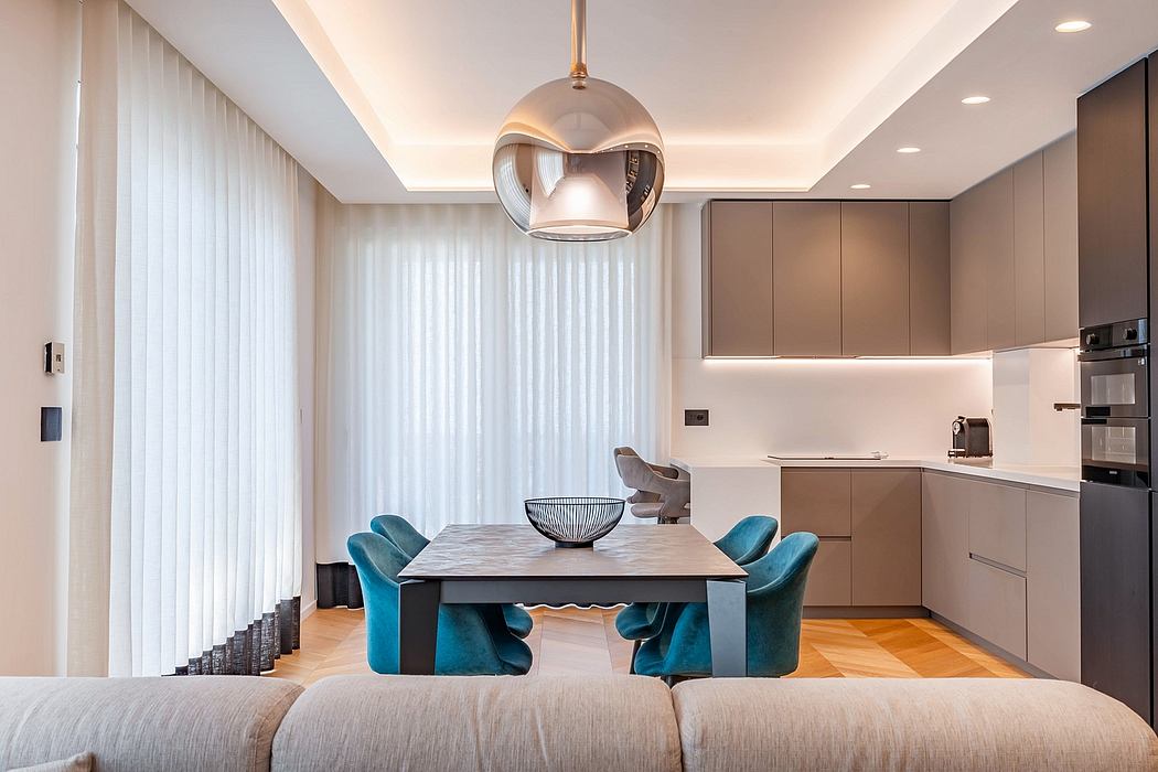 Modern, open-concept kitchen and dining area with sleek cabinetry, plush seating, and a striking pendant light fixture.