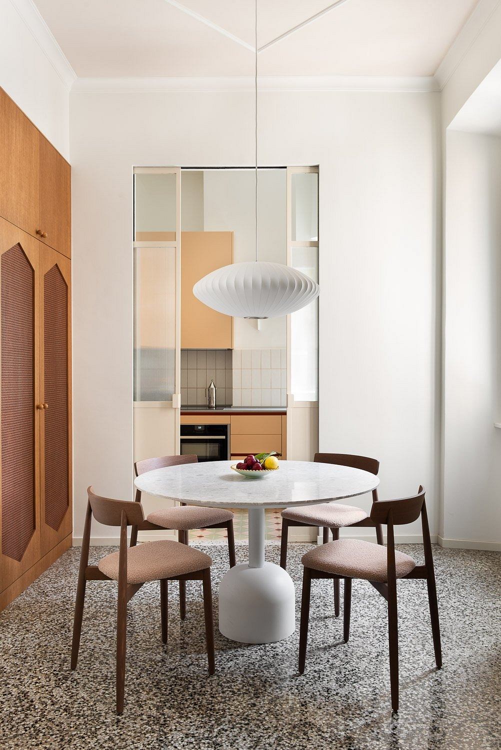 Modern dining area with marble table, wood chairs, and geometric light fixture.