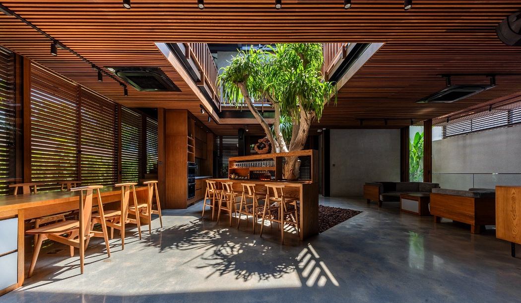 Spacious open-plan interior with wooden beams, furniture, and a central potted plant.