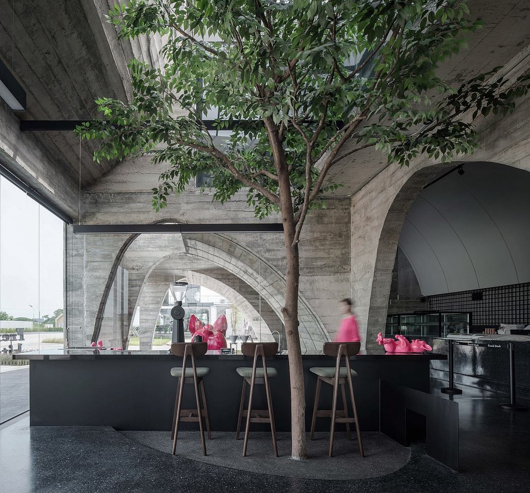 A modern interior design with a tree centerpiece, arched concrete ceiling, and pink accents.