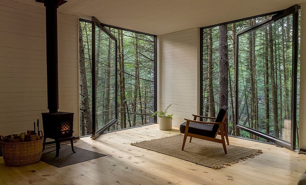 Cozy cabin interior with floor-to-ceiling windows, wood stove, and rustic furnishings.