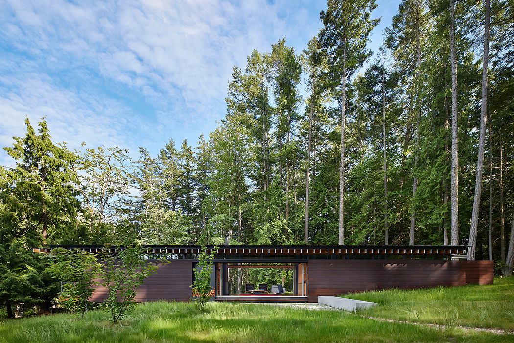Low-profile modern cabin nestled in lush forest, glass walls blending indoor-outdoor.