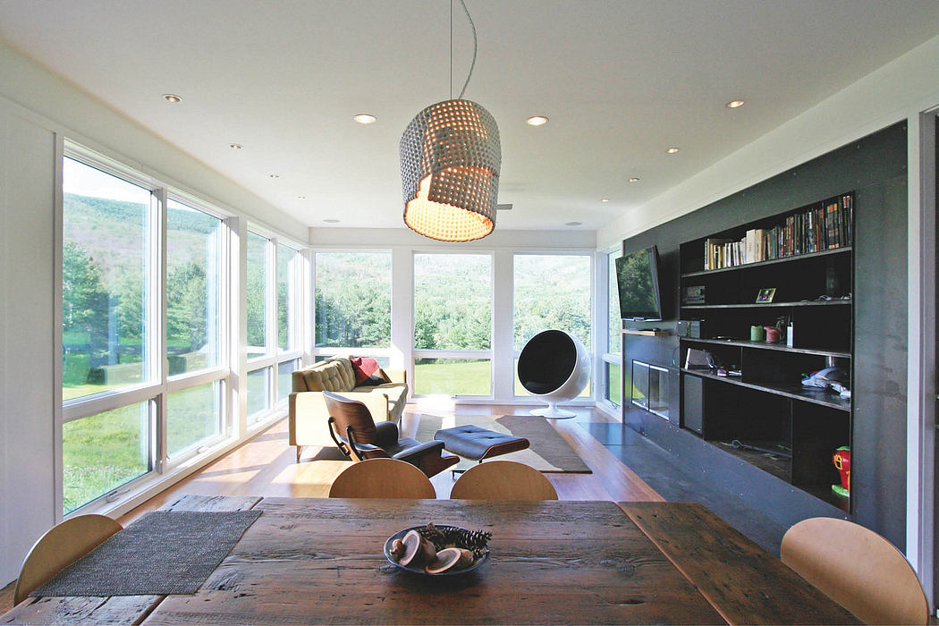 Spacious, modern living area with floor-to-ceiling windows, minimalist furnishings, and a unique hanging light fixture.