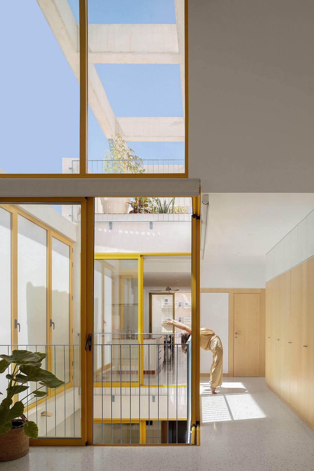 A modern, open-concept interior with large windows, wood accents, and a balcony.