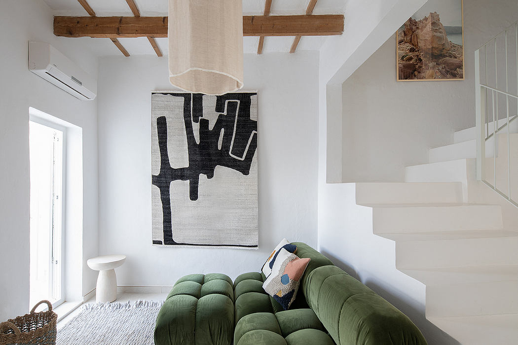 Spacious room with wood beams, white walls, modern furnishings, and abstract artwork.
