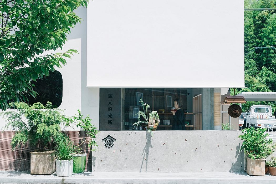 A modern, minimalist building with a large window display showcasing a person inside.