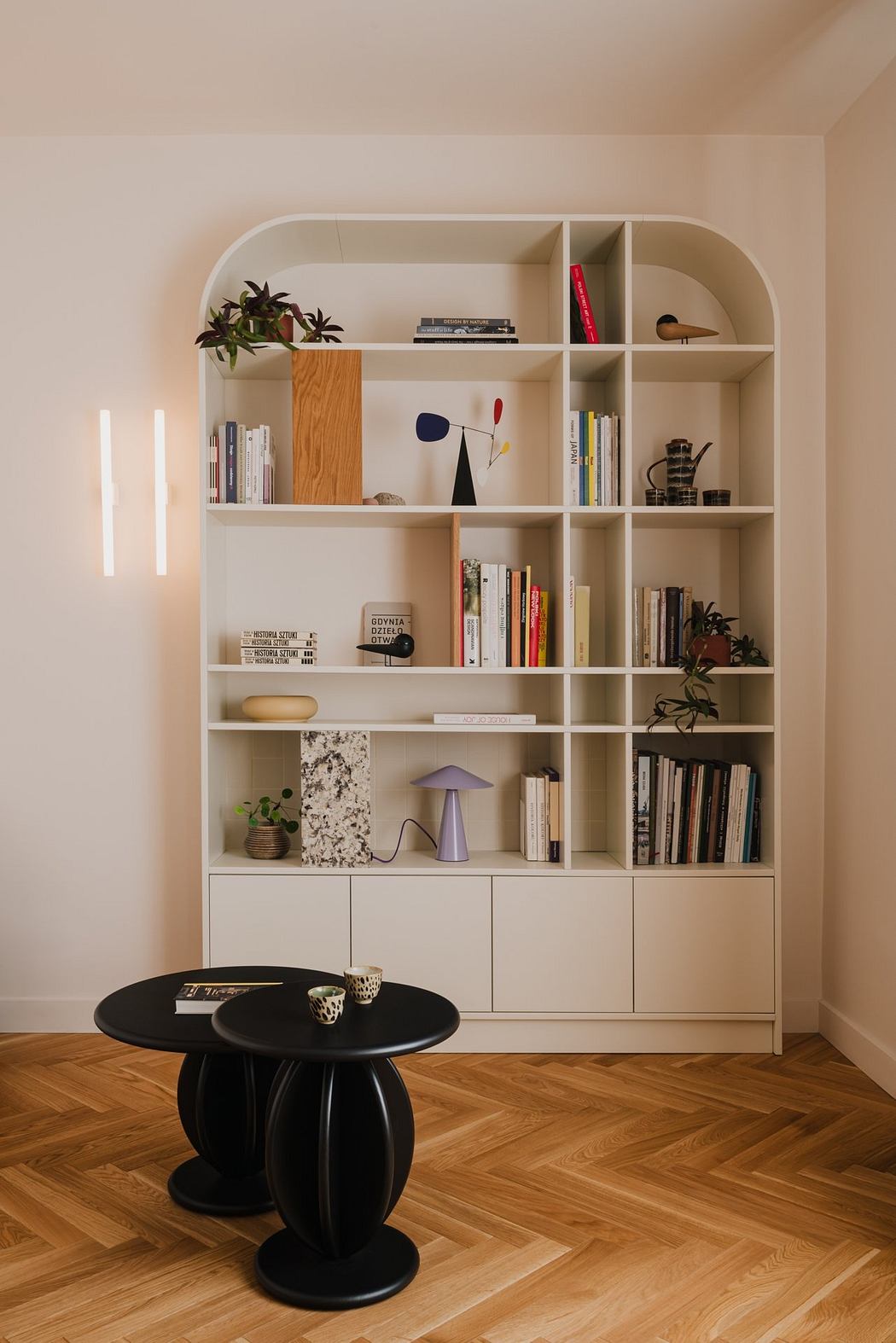 A modern, minimalist bookshelf with a variety of decor and a sleek black side table.