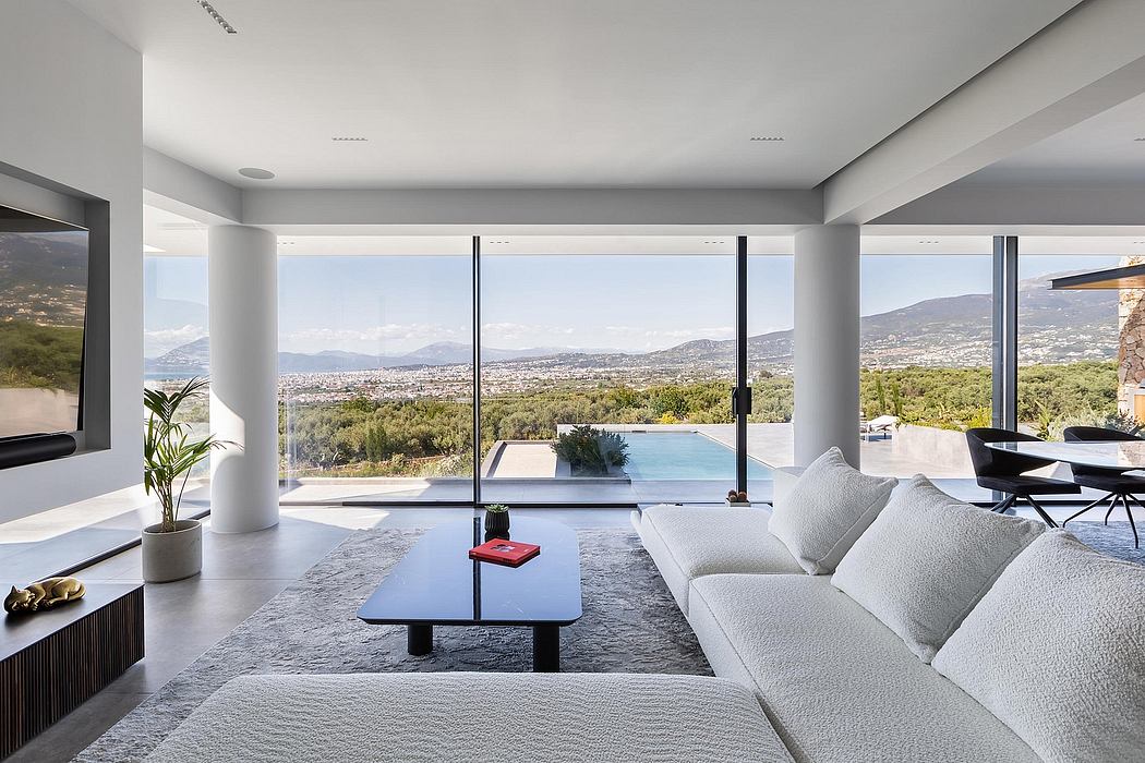 Modern open-concept living room with panoramic mountain views, minimalist furniture, and an outdoor pool.