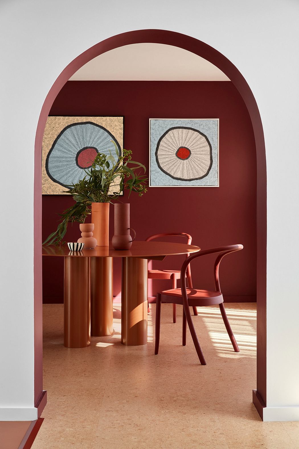A stylish, modern dining area with arched walls, wooden furniture, and abstract artwork.