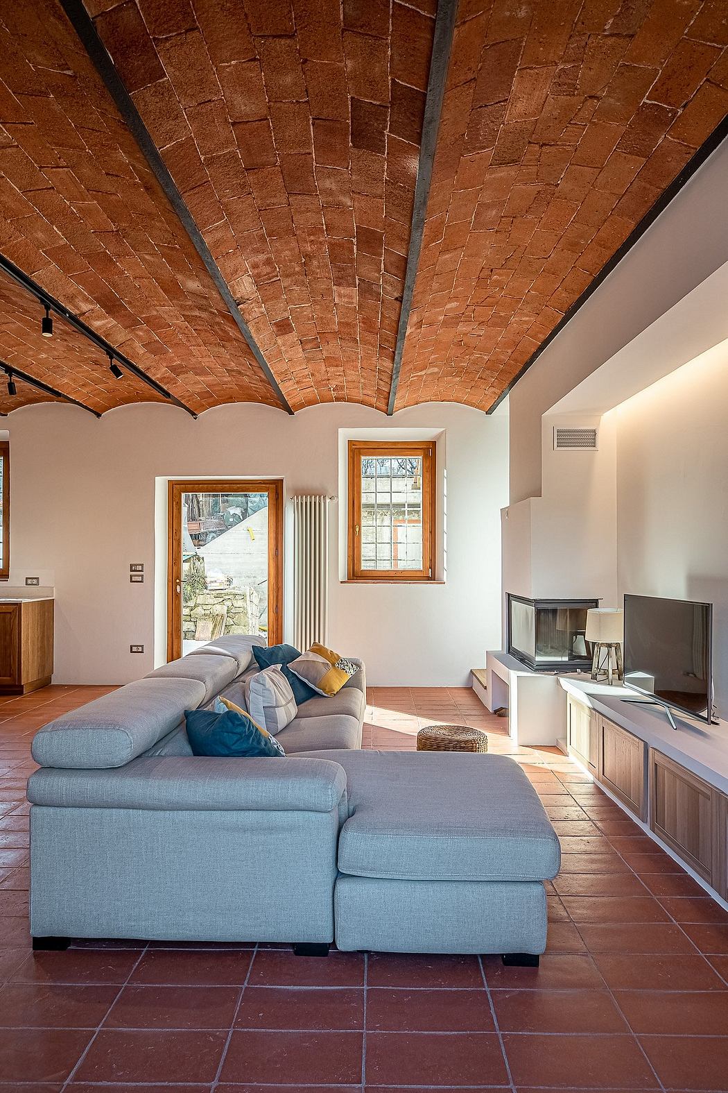 The image showcases a cozy living room with a striking brick vaulted ceiling, creating a warm and rustic ambiance.