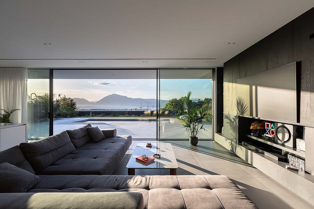 Modern living room with panoramic windows overlooking lush landscape and mountains.