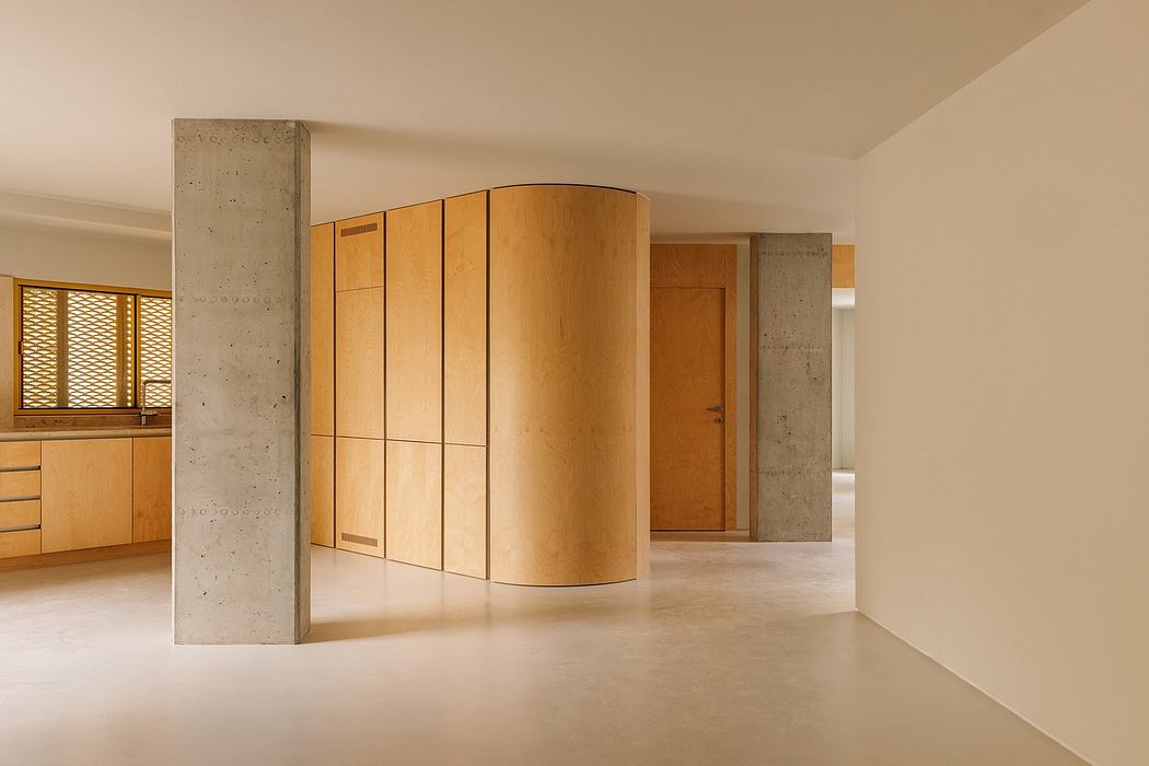 Minimalist interior with curved wooden cabinetry, concrete pillar, and neutral tones.